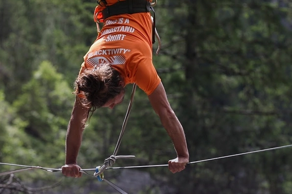 Uma pessoa praticando slackline no alto de uma floresta
